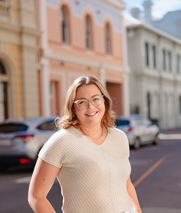 Online postgraduate female student stand on a street near the Fremantle Campus 