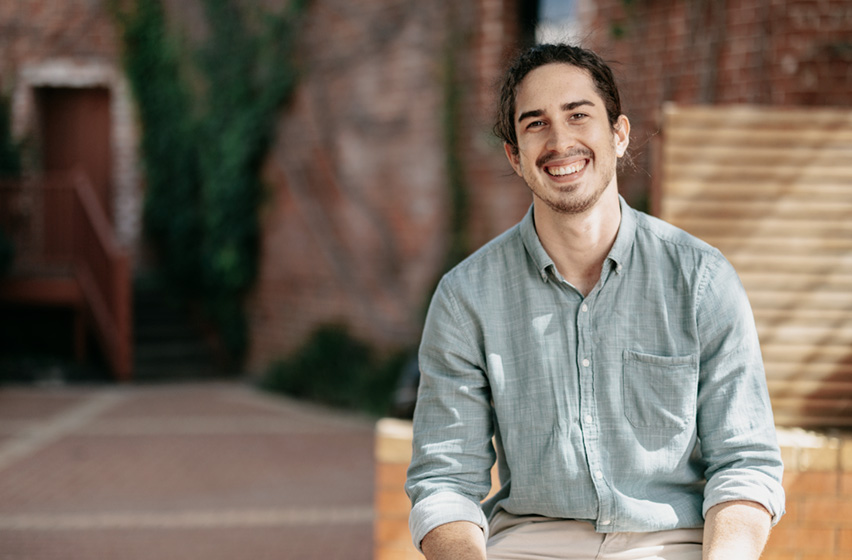 Notre Dame male undergraduate medicine student wearing a green shirt sitting down on the Fremantle Campus 